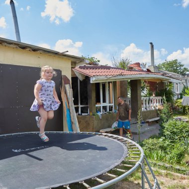 Chernihiv, Ukrayna - 26 Haziran 2022: Kız yıkılmış evine doğru atlıyor. Evi Rus topçuları tarafından tamamen yok edilen Chernihiv 'in sakini..