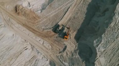 Loader loading sand into heavy dump truck at the opencast mining quarry. Dump truck transports sand in open pit mine. Quarry in which sand and gravel is excavated from the ground