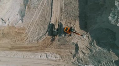 Loader loading sand into heavy dump truck at the opencast mining quarry. Dump truck transports sand in open pit mine. Quarry in which sand and gravel is excavated from the ground