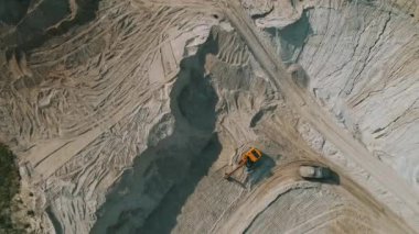 Loader loading sand into heavy dump truck at the opencast mining quarry. Dump truck transports sand in open pit mine. Quarry in which sand and gravel is excavated from the ground