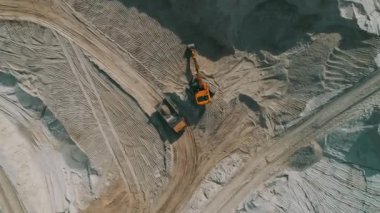 Loader loading sand into heavy dump truck at the opencast mining quarry. Dump truck transports sand in open pit mine. Quarry in which sand and gravel is excavated from the ground