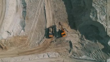 Loader loading sand into heavy dump truck at the opencast mining quarry. Dump truck transports sand in open pit mine. Quarry in which sand and gravel is excavated from the ground