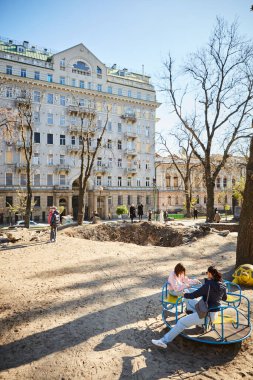 Kyiv, Ukrayna - 16 Ekim 2022: Başkentin merkezindeki bir çocuk parkında Rus roketinin patlamasından kaynaklanan bacanın yakınındaki insanlar