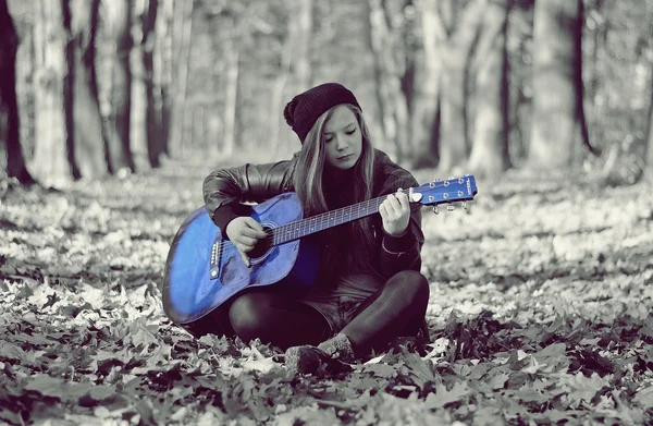 Flicka med gitarr i höst park — Stockfoto