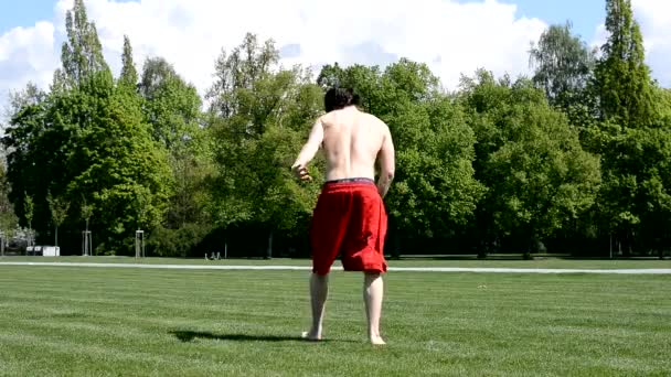 Jonge jongen springt spiegelen terug in het park — Stockvideo