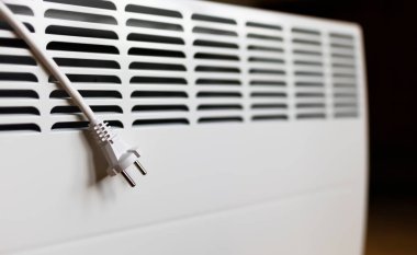 Electrical plug with wire on a heater. Saving electricity, save power, heating season or energy crisis concept. 