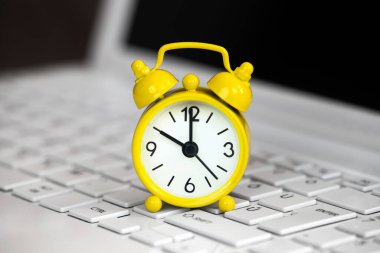 Beyaz dizüstü bilgisayarda sarı alarm saati, gün ışığında tasarruf zamanı...