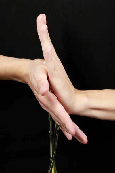 Avuç içleri arasındaki sıvı siyah arkaplanda