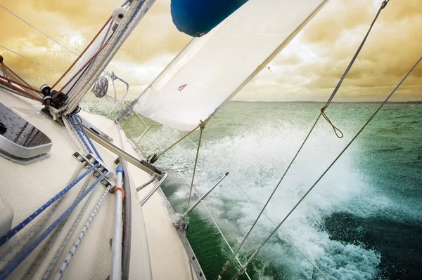 hızlı su sıçramasına dramatik gökyüzü altında güverte ile yelken