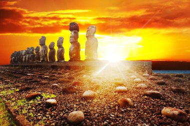 Standing moais in Easter Island in dramatic orange sunset clipart