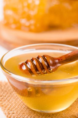Honey dripping from a wooden honey dipper on white background. Healthy organic food concept. 