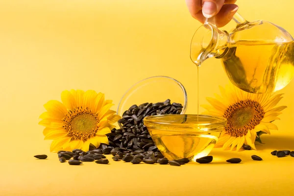 Sunflower oil and sunflower seeds on yellow background. Organic and eco food concept. Healthy food and fats.
