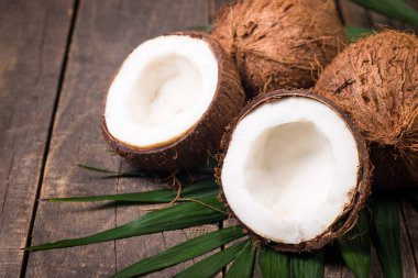 Ahşap arka planda yeşil yapraklı, yarım kesilmiş hindistan cevizi.. 