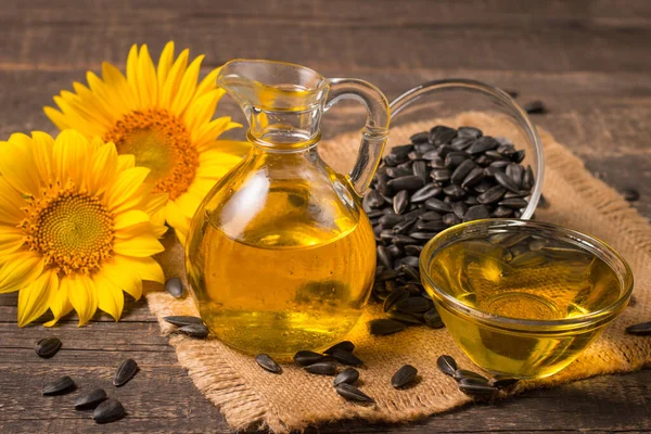 Sunflower oil and sunflower seeds on traditional rustic wooden background. Organic and eco food concept. Healthy food and fats.