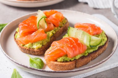 Sağlıklı kahvaltı için füme ve tuzlu somon balıklı açık sandviç. Bruschetta tostunda alabalık ve avokado.. 