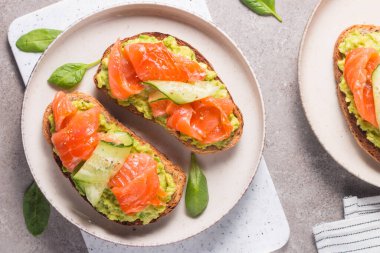 Sağlıklı kahvaltı için füme ve tuzlu somon balıklı açık sandviç. Bruschetta tostunda alabalık ve avokado.. 
