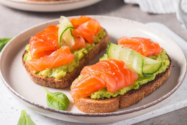 Open sandwich with smoked and salted salmon for healthy breakfast. Trout and avocado on bruschetta toast.