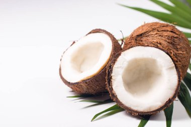 Beyaz arka planda yeşil yapraklı, yarım kesilmiş hindistan cevizi. Ayrı bir kavram.