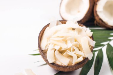 Hindistan cevizi ve beyaz arka planda yeşil yapraklı hindistan cevizi cipsi. Ayrı bir kavram.