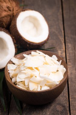 Hindistan cevizi ve ahşap arka planda yeşil yapraklı hindistan cevizi cipsi.. 