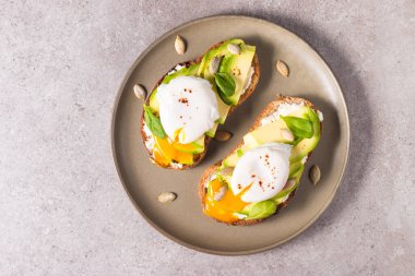Avokado, krem peynirli tost çavdar ekmeği ve haşlanmış yumurta. Sağlıklı kahvaltı konsepti için açık sandviç..