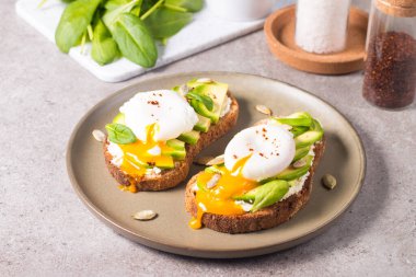 Avokado, krem peynirli tost çavdar ekmeği ve haşlanmış yumurta. Sağlıklı kahvaltı konsepti için açık sandviç..