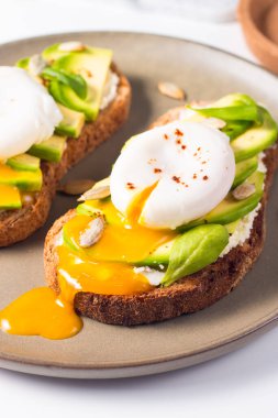 Avokado, krem peynirli tost çavdar ekmeği ve haşlanmış yumurta. Sağlıklı kahvaltı konsepti için açık sandviç..