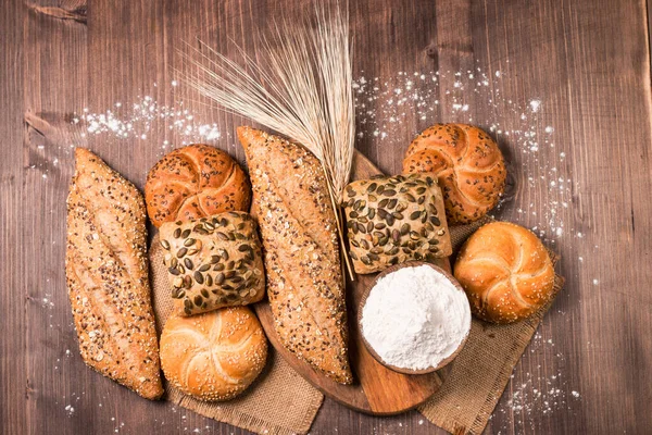 Assortment of baked bread with seeds on a wooden table background. Bakery. Food security concept.