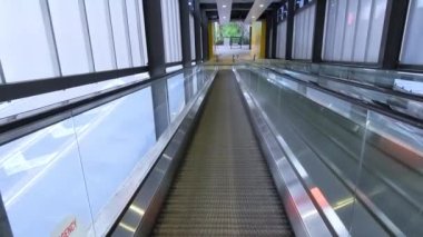 Traveling on an empty moving travelator in an empty corridor, no people in sight, wide shot