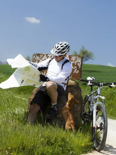 Велосипедист на зеленой сельской местности с собакой — стоковое фото