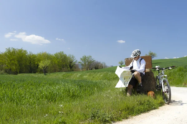 Cyclist on green countryside wit his dog — Stock Photo, Image