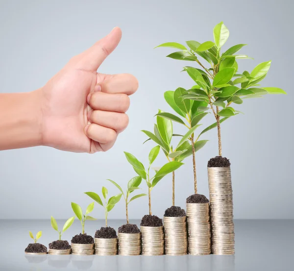 Empresário segurando planta brotando de um punhado de moedas — Fotografia de Stock