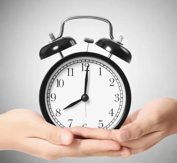 Holding alarm clock in hands — Stock Photo, Image