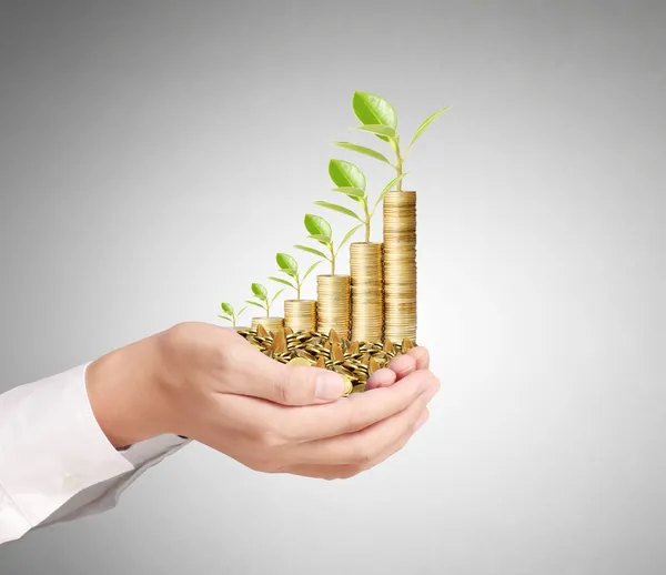 Empresario sosteniendo planta brotando de un puñado de monedas — Foto de Stock