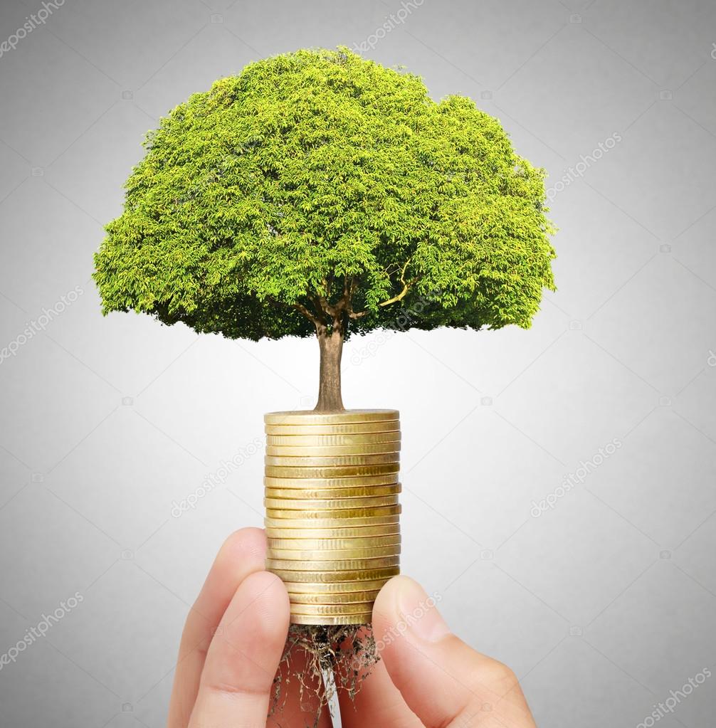 Businessman holding plant sprouting from  handful of coins 