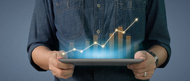 İş adamı grafik büyümesi ve tablet üzerinde yaptığı işte olumlu göstergeler artışı planlıyor