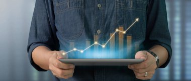 İş adamı grafik büyümesi ve tablet üzerinde yaptığı işte olumlu göstergeler artışı planlıyor