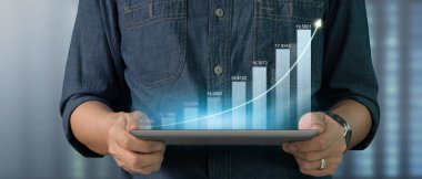İş adamı grafik büyümesi ve tablet üzerinde yaptığı işte olumlu göstergeler artışı planlıyor