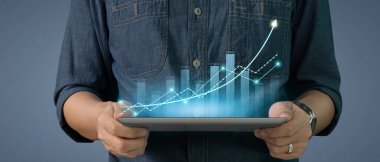 İş adamı grafik büyümesi ve tablet üzerinde yaptığı işte olumlu göstergeler artışı planlıyor