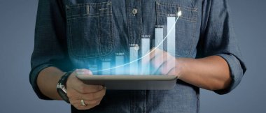İş adamı grafik büyümesi ve tablet üzerinde yaptığı işte olumlu göstergeler artışı planlıyor