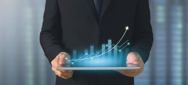 İşadamı, elinde tabletle iş yerinde grafik büyümesi ve grafik artışı planlıyor