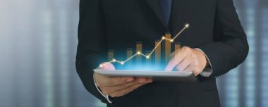 İşadamı, elinde tabletle iş yerinde grafik büyümesi ve grafik artışı planlıyor