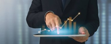 İşadamı, elinde tabletle iş yerinde grafik büyümesi ve grafik artışı planlıyor