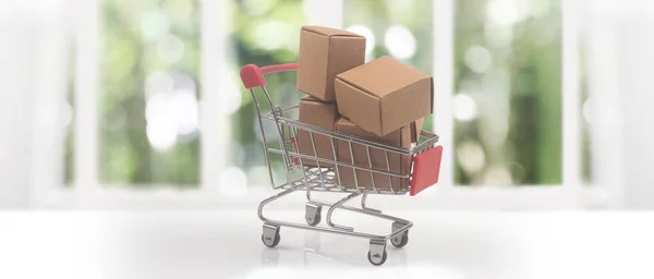 Toy shopping cart with boxes shopping and delivery concept. Consumer society trend