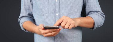 Akıllı telefonu elinde tutan ve ekrana dokunan adam.