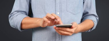 Akıllı telefonu elinde tutan ve ekrana dokunan adam.