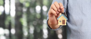 Emlakçı elinde evin anahtarlarını veriyor.