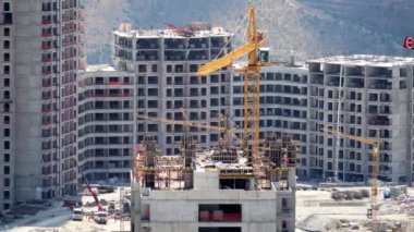 Cinematic 8K 7680x4320.Cranes and construction workers working at a major.Builders on building site.Transporting wall molds at skyscraper.Concrete and iron combination.Yellow crane mixed compex crowd.
