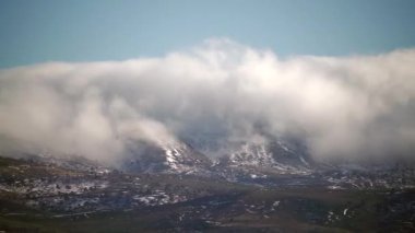 8K 4320p 7680x4320.Bulut dağ sıralarından aşağı akıyor. Tepelerin kıvrımlarında yatan sis. Ağaçsız karasal alanlar. Baharda tepeler. Doğada güneşli standart bir gün. Sis kayboluyor..