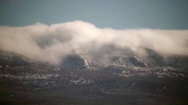8K 4320p 7680x4320.Bulut dağ sıralarından aşağı akıyor. Tepelerin kıvrımlarında yatan sis. Ağaçsız karasal alanlar. Baharda tepeler. Doğada güneşli standart bir gün. Sis kayboluyor..